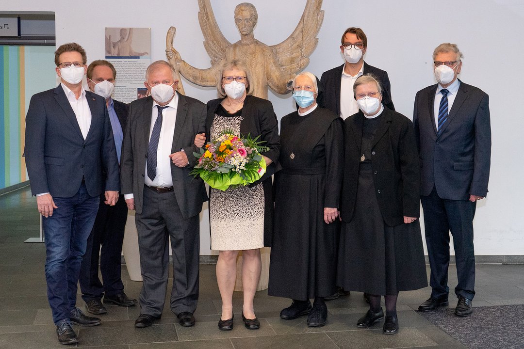 Mehrere Personen stehen vor der Engelsskulptur der Raphaelsklinik