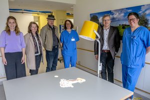Spender und Spendenempfänger stehen um einen Tisch, auf den ein Hund projiziert wird.
