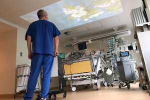 Ein Pfleger steht an einem Bett