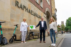 Drei Personen stehen vor dem Schriftzug Raphaelsklinik