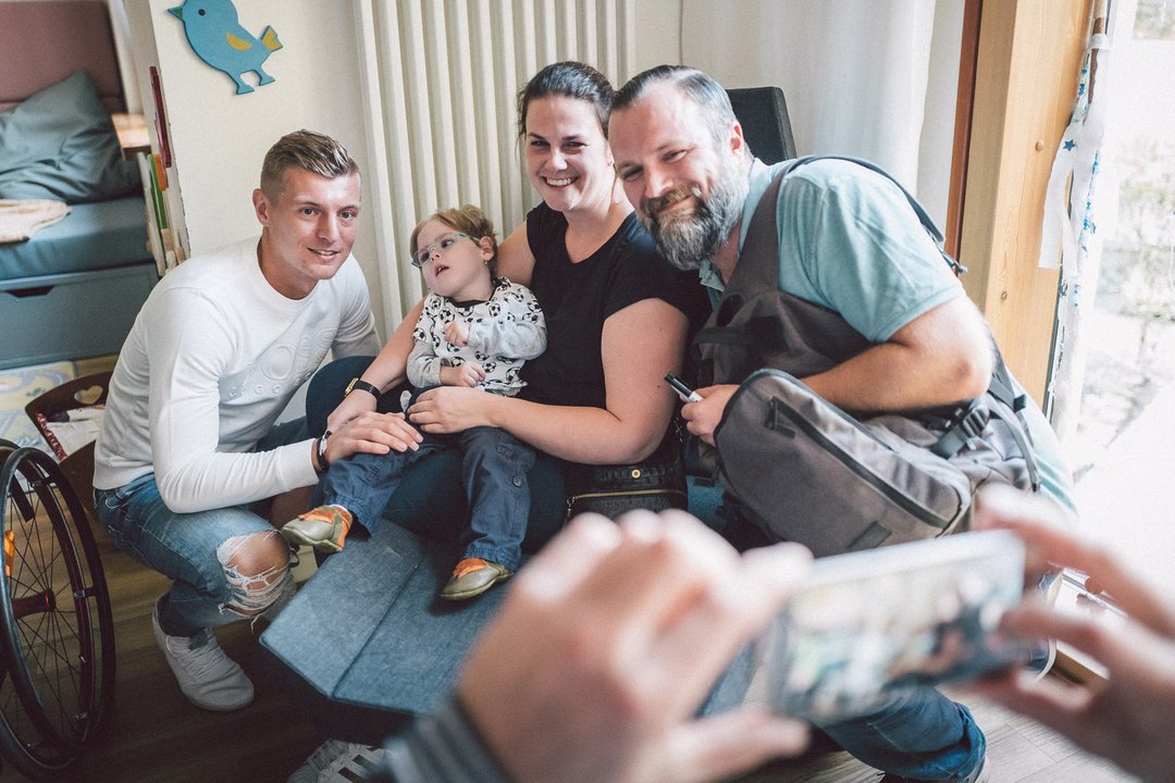 Toni Kroos hockt neben einem Kind