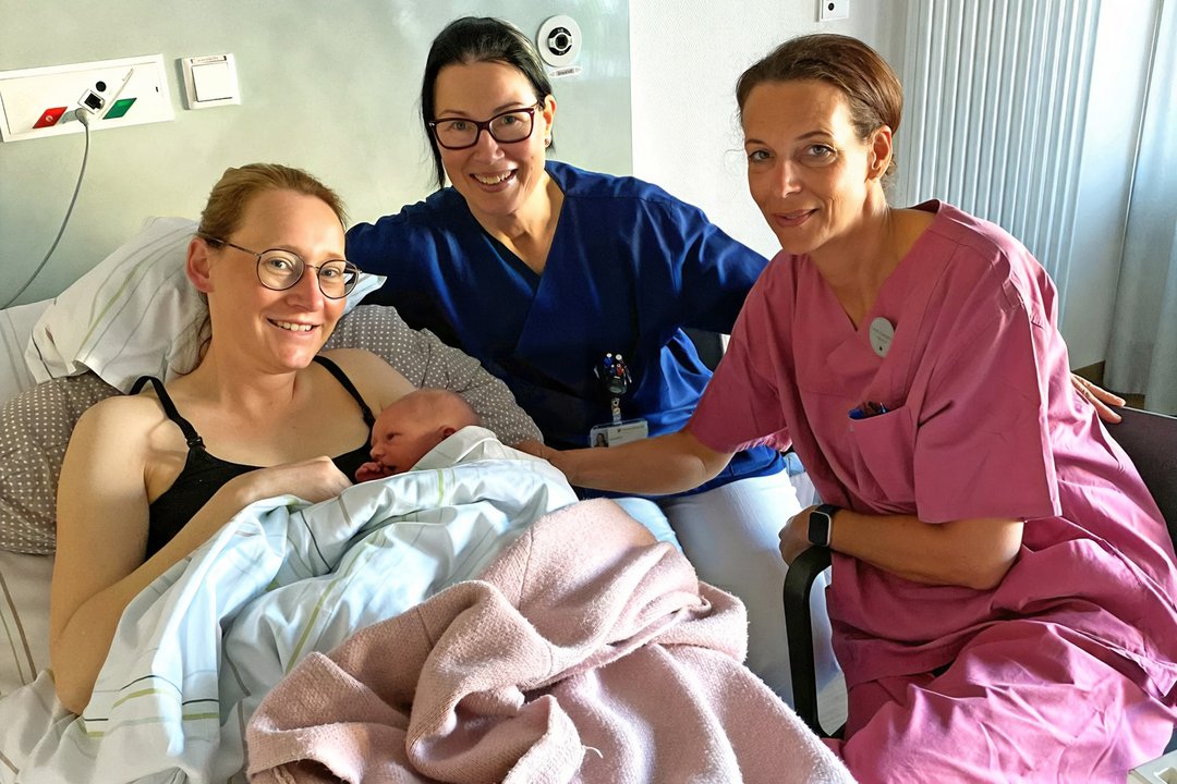 Drei Personen gruppieren sich um ein Baby herum