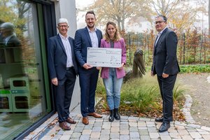 Vier Personen halten einen großen Scheck