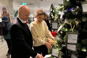 Fredrik Horstmann, Geschäftsführer der Galeria Münster, und Dr. Martina Klein, Fundraising der Alexianer, stöbern in den Weihnachtswünschen im Charity-Wald in der Galeria. Rund 700 Herzenswünsche konnten hierüber erfüllt werden. 