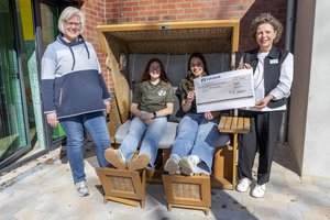 Zwei junge Frauen in einem Strandkorb, zwei ältere daneben
