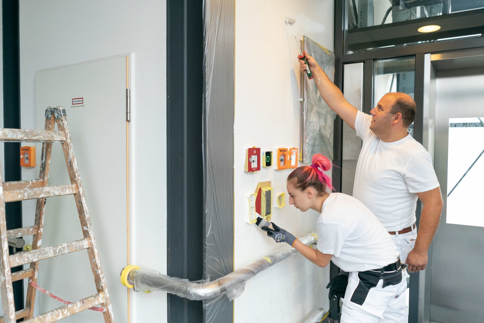 Zwei Menschen streichen eine Wand