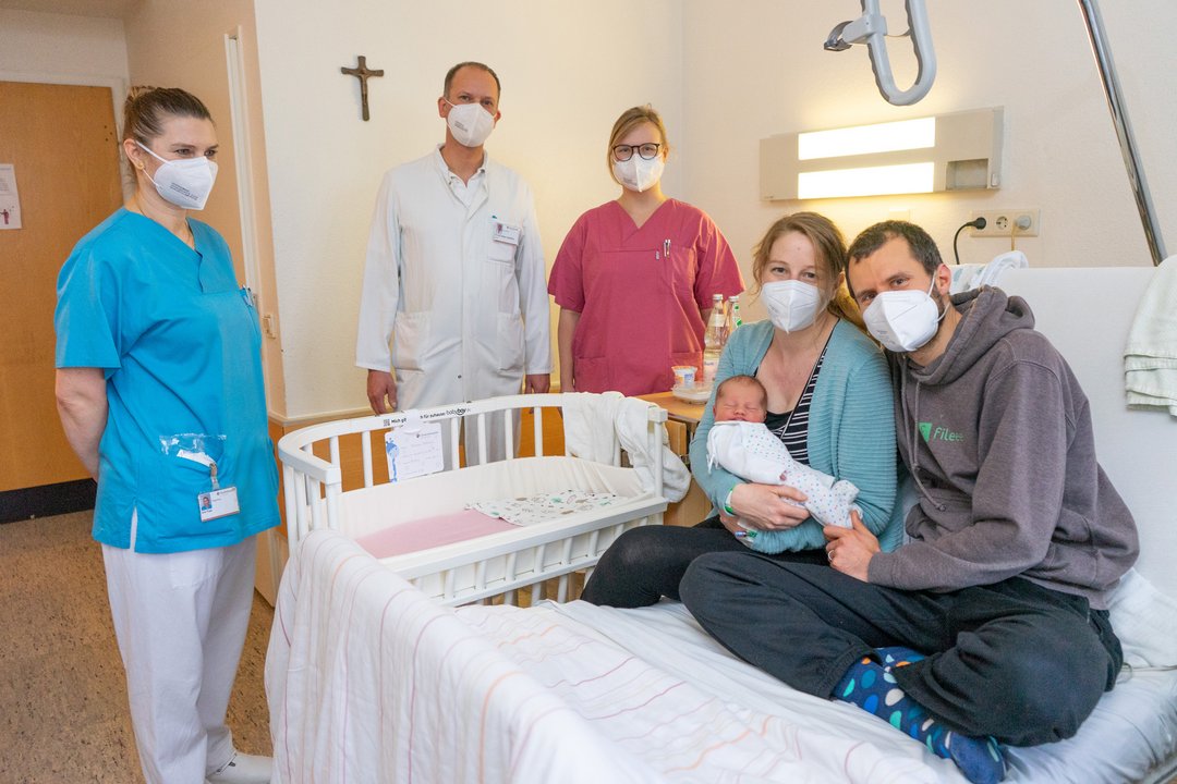 Ehepaar sitzt mit ihrem Baby auf einem Bett