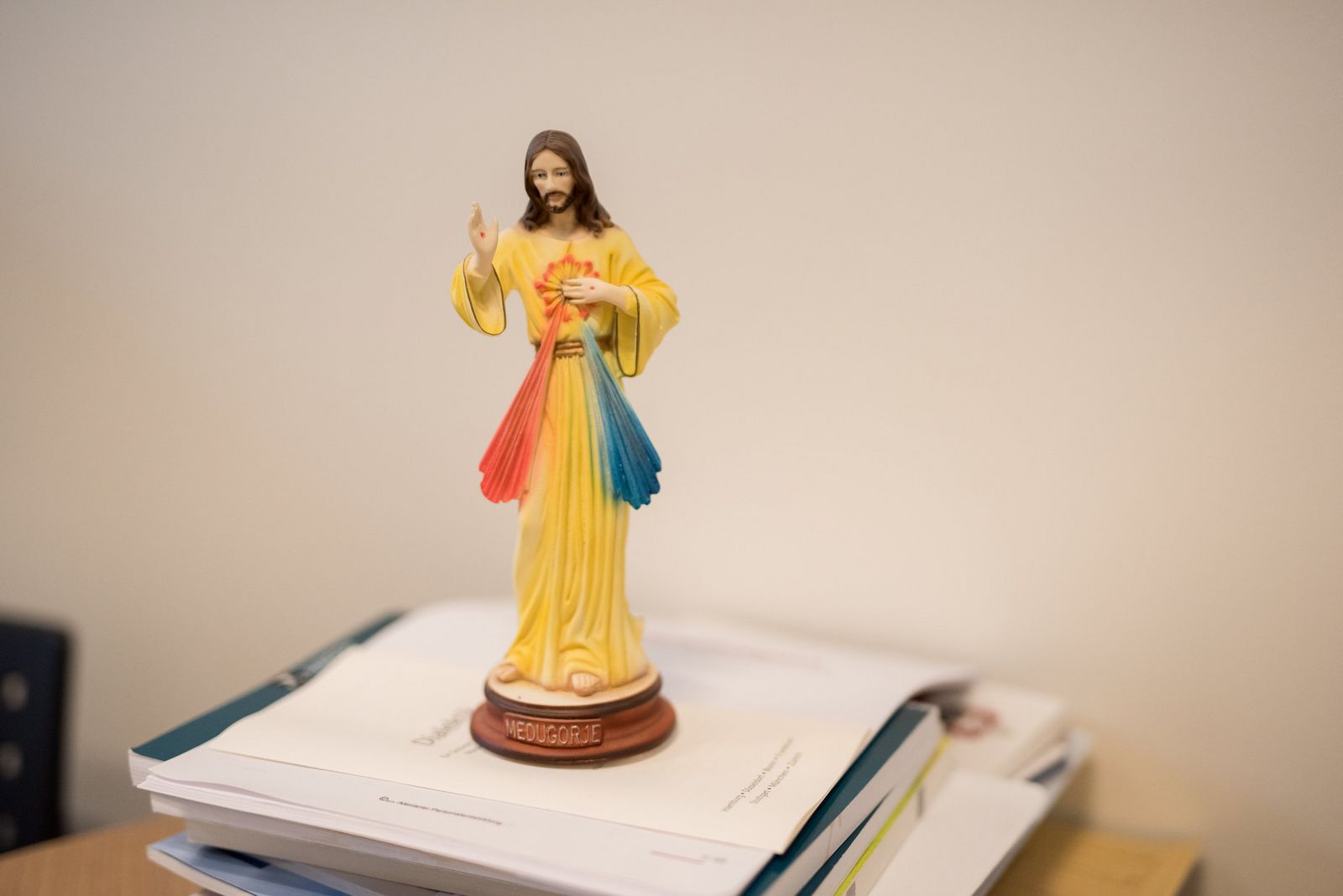 Eine Jesusfigur steht auf einem Stapel Unterlagen in einem Büro