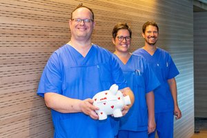 Drei Personen halten ein Sparschwein