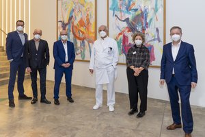 Mehrere Personen stehen vor zwei Bildern