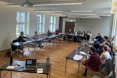 Blick in einen Konferenzraum, Menschen sitzen an Tischen